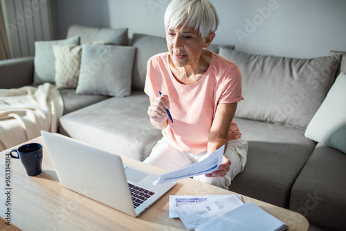 Senior woman managing finances on laptop at home photo