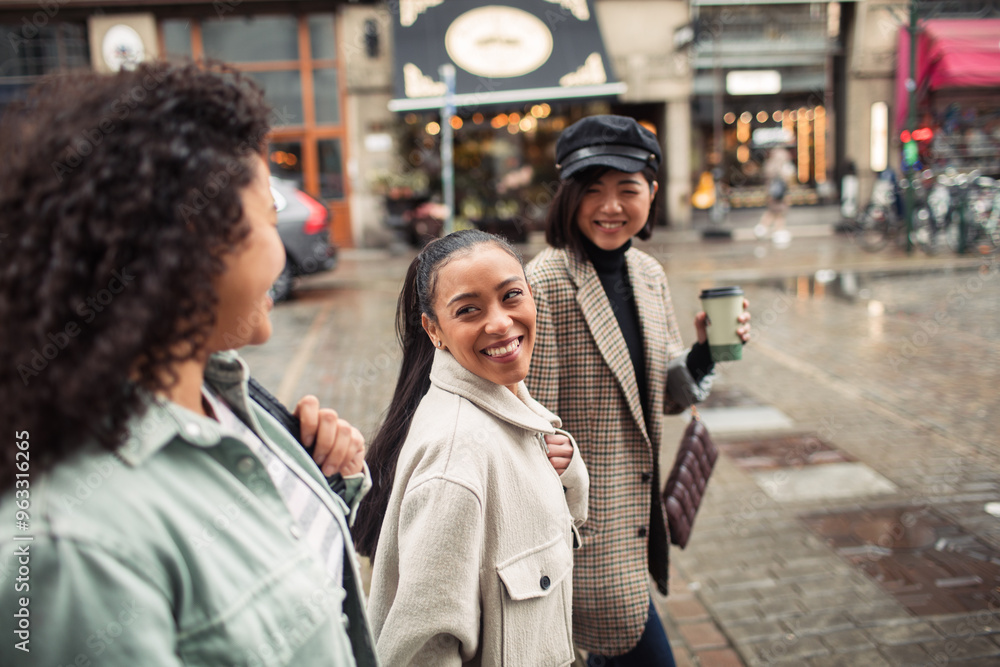 Three diverse female friends walking together on city street Three diverse female friends walking together on city street