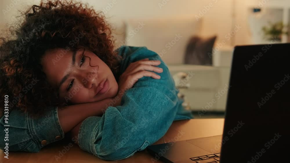 Tired young woman falls asleep with her head on her hands while sitting at table with laptop Tired young woman falls asleep with her head on her hands while sitting at table with laptop