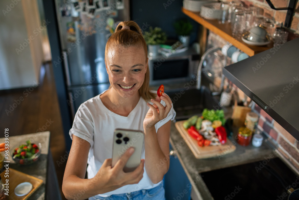 Smiling young woman using smartphone in modern kitchen Smiling young woman using smartphone in modern kitchen