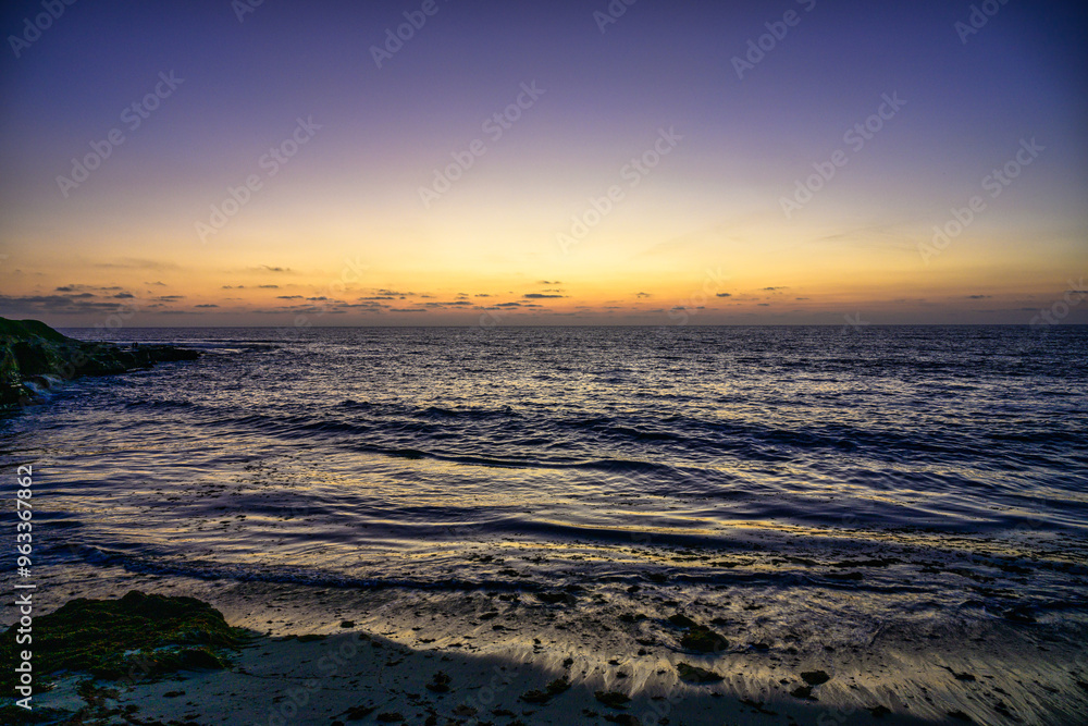 Fototapeta premium 2023-12-31 A MOODY SUNSET ALONG THE LA JOLLA COASTLINE WITH CLAM WATERS AND A YELLOW TINT ON TH EHORIZION NEAR SAN DIEGO CALIFORNIA-