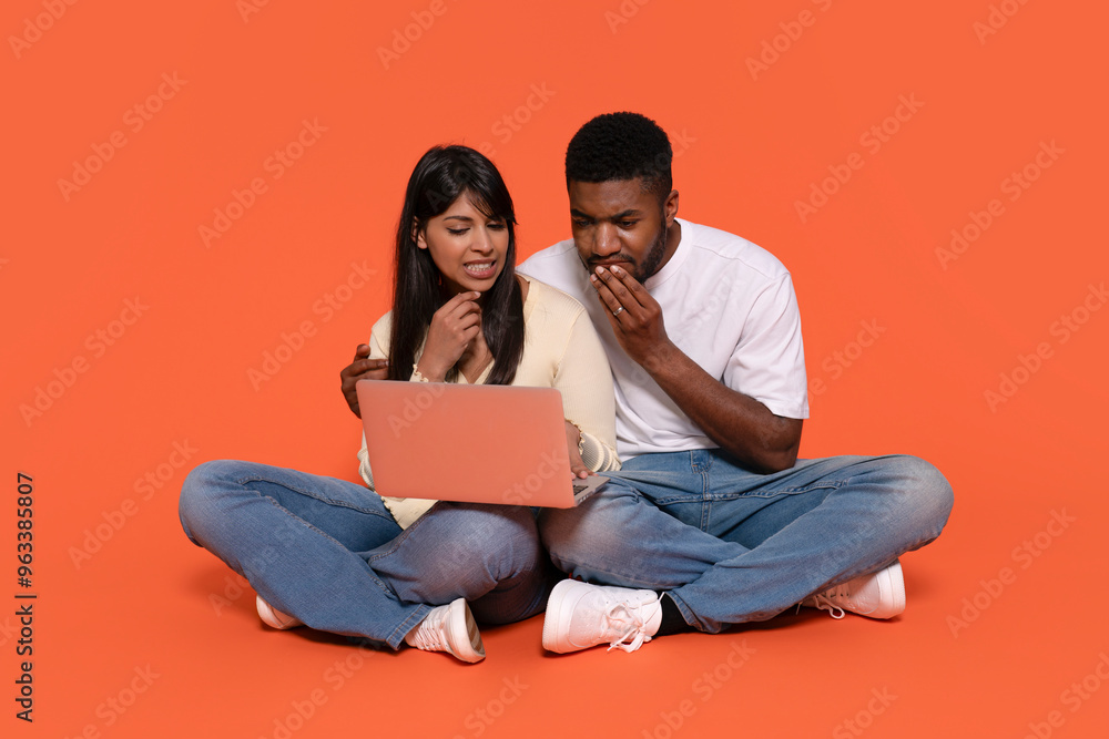 A Couple Sharing Bad News While Exploring Online Content on a Laptop Against a Vibrant Backdrop A Couple Sharing Bad News While Exploring Online Content on a Laptop Against a Vibrant Backdrop