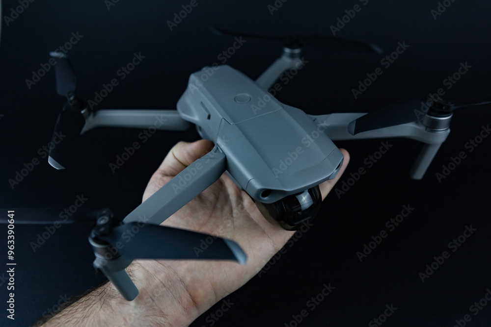 a man's hand holds a drone in his hands against the black background a man's hand holds a drone in his hands against the black background