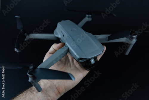 a man's hand holds a drone in his hands against the black background