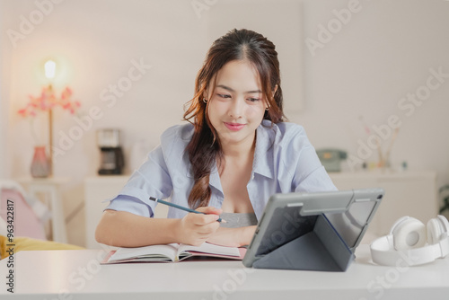 Young happy professional business woman worker employee sitting at desk working on laptop in corporate office. Smiling female student using computer technology learning online, doing web research.