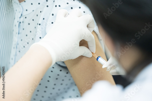 Close up doctor holding syringe make injection to patient in medical mask.Covid-19 or coronavirus vaccine.Vaccine for protection HPV (Human Papillomavirus) infection photo