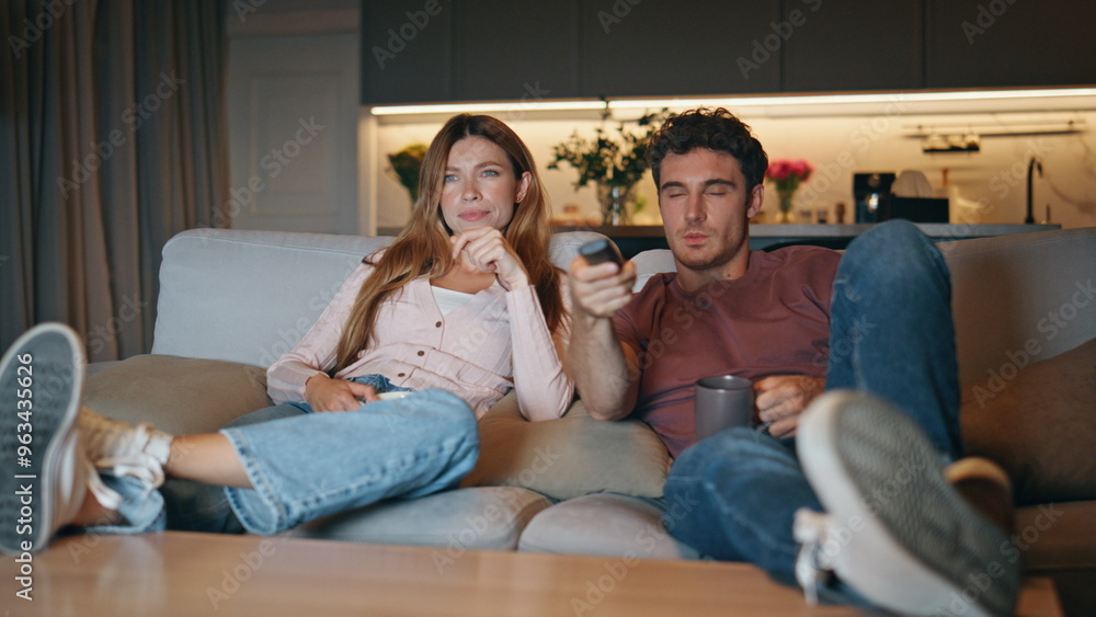 Young pair watching television switching channels couch. Couple choosing movie Young pair watching television switching channels couch. Couple choosing movie