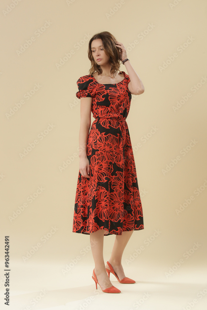 Serie of studio photos of young female model in black and orange midi dress with short puff sleeves Serie of studio photos of young female model in black and orange midi dress with short puff sleeves