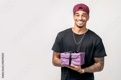 A good-looking African-American guy holds up a gift box and smiles genuinely. Close-up portrait on white background with copied space for text. photo