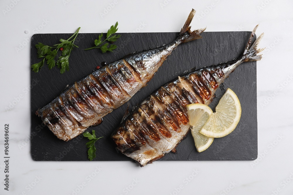 Delicious grilled mackerel, parsley, spices and lemon on white table, top view Delicious grilled mackerel, parsley, spices and lemon on white table, top view