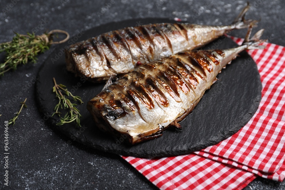 Delicious grilled mackerel, thyme and napkin on dark textured table, closeup Delicious grilled mackerel, thyme and napkin on dark textured table, closeup