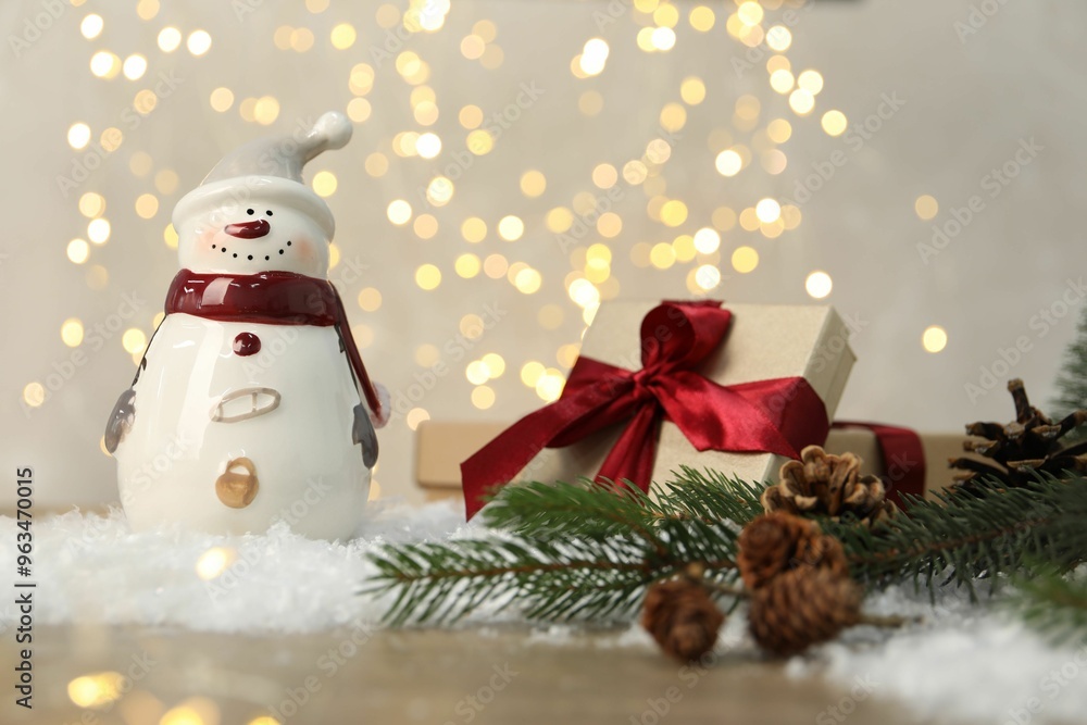 Funny snowman figure and other decor on table against blurred lights Funny snowman figure and other decor on table against blurred lights