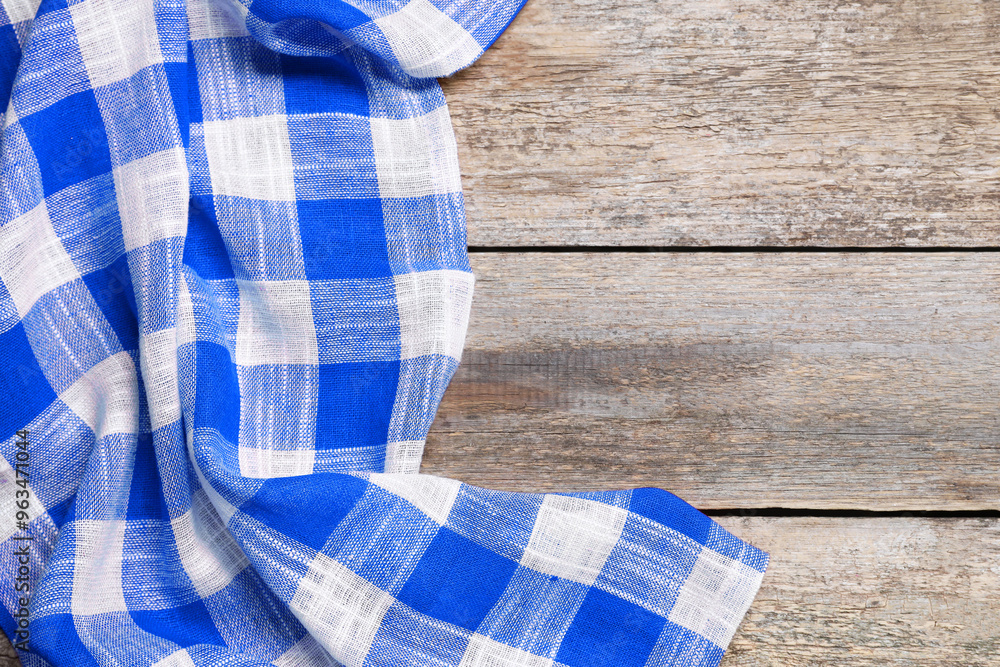 Blue checkered gingham fabric on wooden table Blue checkered gingham fabric on wooden table