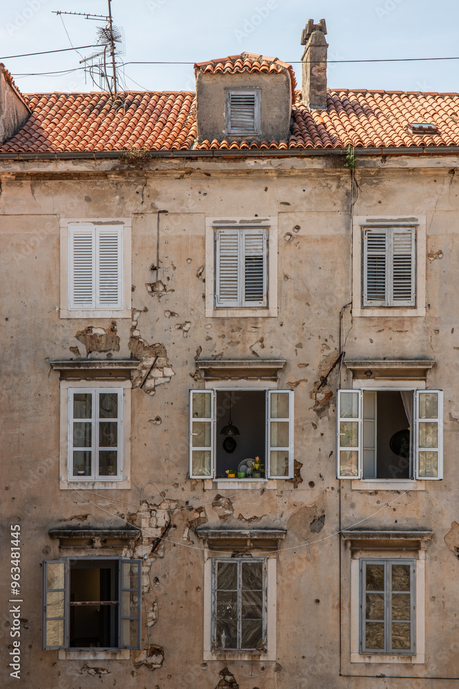 Window of an old building showing bullet holes from the Balkan War. Window front or house front in the historic old town of Zadar, Adriatic Sea, Dalmatia, Croatia Window of an old building showing bullet holes from the Balkan War. Window front or house front in the historic old town of Zadar, Adriatic Sea, Dalmatia, Croatia