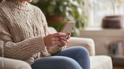 Older Woman Using Mobile Smart Phone Technology Device Sitting On Couch At Home