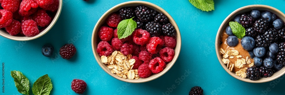 Three bowls filled with vibrant smoothie bowls, each featuring a unique combination of fresh berries, almonds, and a hint of mint. The blue background adds a pop of color and freshness to the image. Three bowls filled with vibrant smoothie bowls, each featuring a unique combination of fresh berries, almonds, and a hint of mint. The blue background adds a pop of color and freshness to the image.