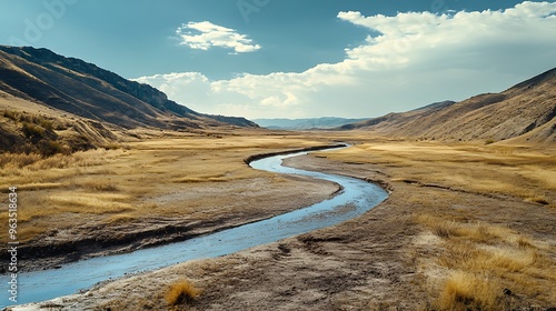 An empty, dry riverbed winding through a formerly lush valley, illustrating the dramatic impact of water scarcity and drought on the environment. photo