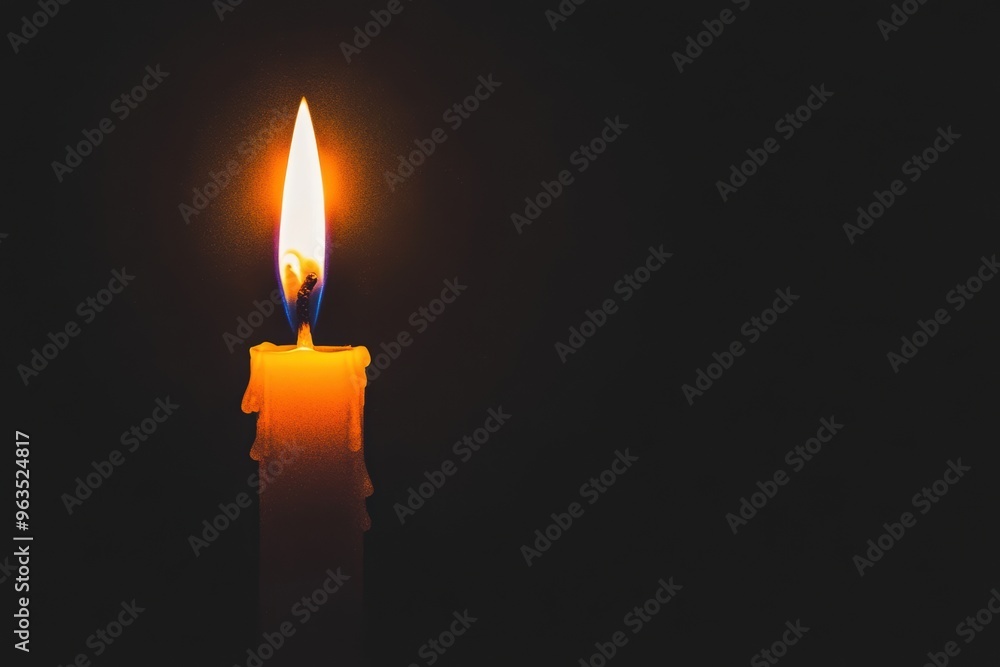 Single burning candle in the dark, casting a warm glow in the surrounding darkness. Single burning candle in the dark, casting a warm glow in the surrounding darkness.