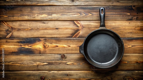 meal preparation, homeware, wooden table, aerial, An empty cast iron skillet is placed on a wooden table against a rustic wood background creating a warm and inviting scene