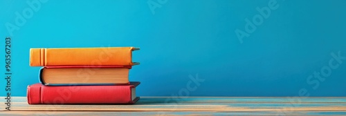 Stack of Three Books on Wooden Table Against Blue Background