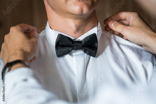 Elegant Preparation: Gentleman Adjusting Classic Black Bow Tie for a Formal Event