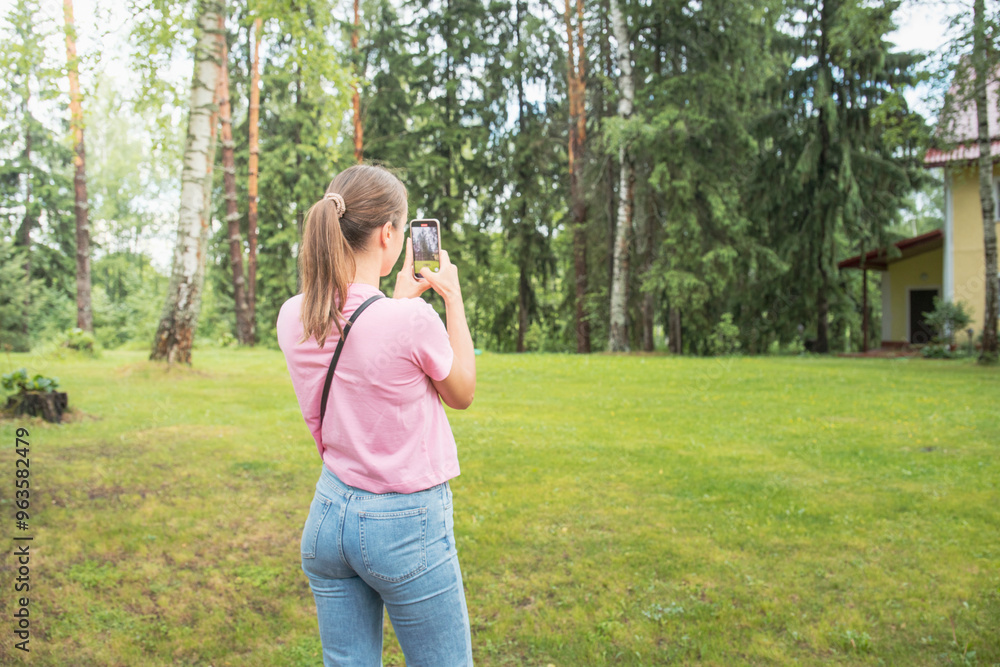 A woman is taking a picture of a tree with her cell phone A woman is taking a picture of a tree with her cell phone