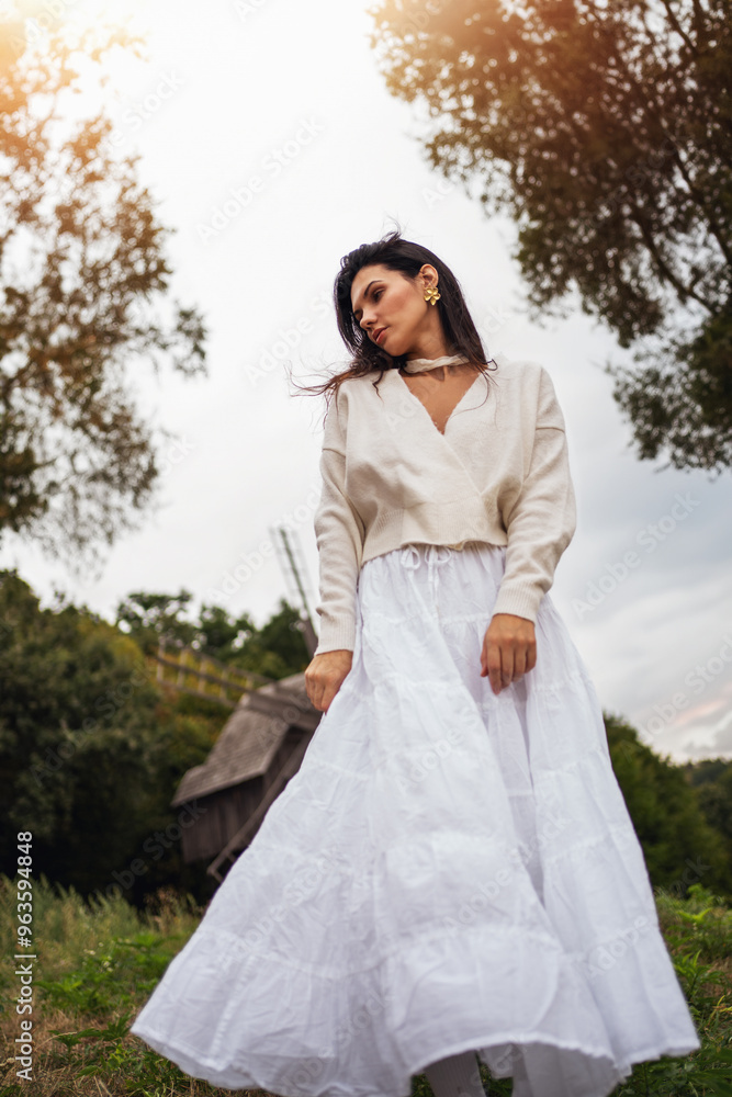 Retro style. Full-length portrait of a young beautiful girl with black chic hair in a white dress against a background of a forest and a red sunset. Retro style. Full-length portrait of a young beautiful girl with black chic hair in a white dress against a background of a forest and a red sunset.