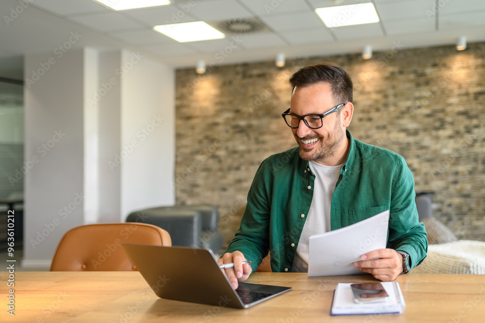 Portrait of handsome manager analyzing financial reports over computer at his workplace in modern office Portrait of handsome manager analyzing financial reports over computer at his workplace in modern office