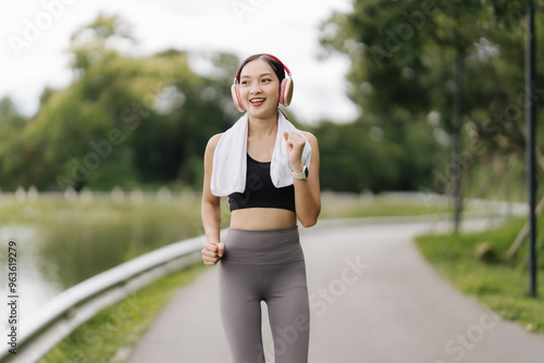 Energetic Jogger: A young woman in athletic wear with headphones runs along a path in a park, radiating positivity and energy while enjoying her workout. 