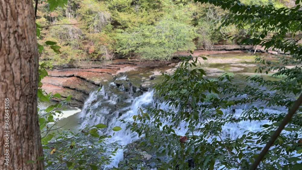 Captivating waterfall cascading over rocks in a serene forest setting during early autumn Captivating waterfall cascading over rocks in a serene forest setting during early autumn