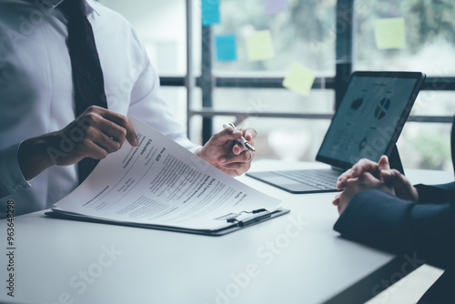 Job Interview Focus: A focused professional in a business suit, reviewing a resume in a job interview, demonstrates the importance of preparation and presentation during the hiring process.  photo