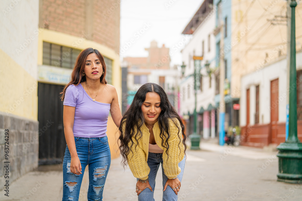 Woman helping her friend who feels sick while walking in the city Woman helping her friend who feels sick while walking in the city