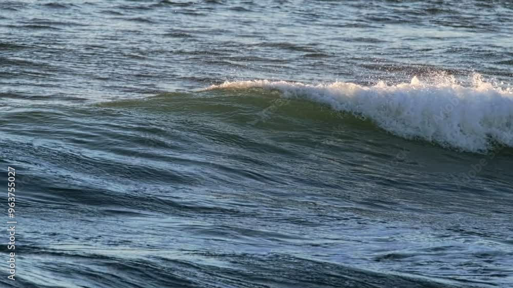 Breaking ocean wave on sunset backlit with sun. Costa da Caparica, Portugal. Slow motion Breaking ocean wave on sunset backlit with sun. Costa da Caparica, Portugal. Slow motion