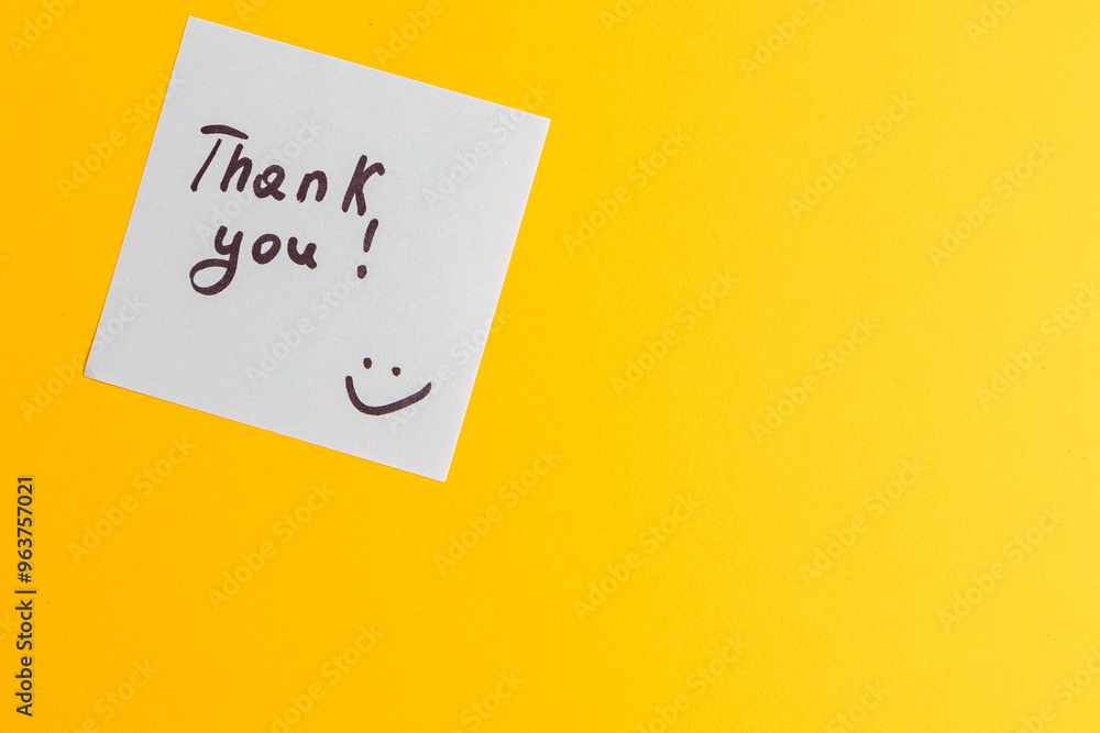 The word thank you on a white piece of paper on a yellow background The word thank you on a white piece of paper on a yellow background