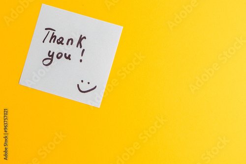 The word thank you on a white piece of paper on a yellow background