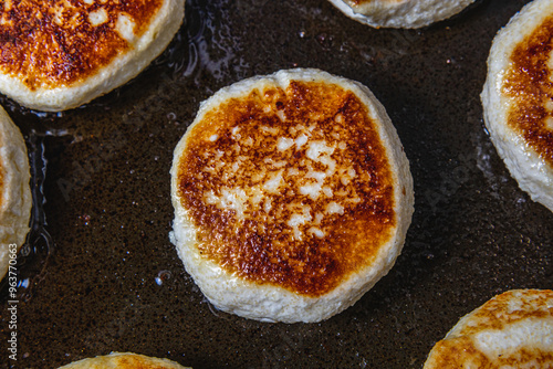 Cottage cheese pancakes are fried in a pan before being pulled out close up photo