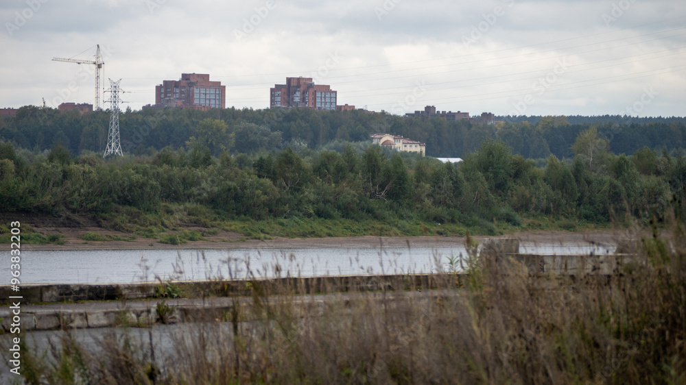 A large construction site is visible in the distance, with a river A large construction site is visible in the distance, with a river