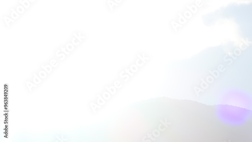 Ethereal overexposed mountain peak and sky with lens flare