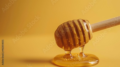 Honey dripping from wooden honey dipper over yellow background. Sweet bee product for copyspace photo