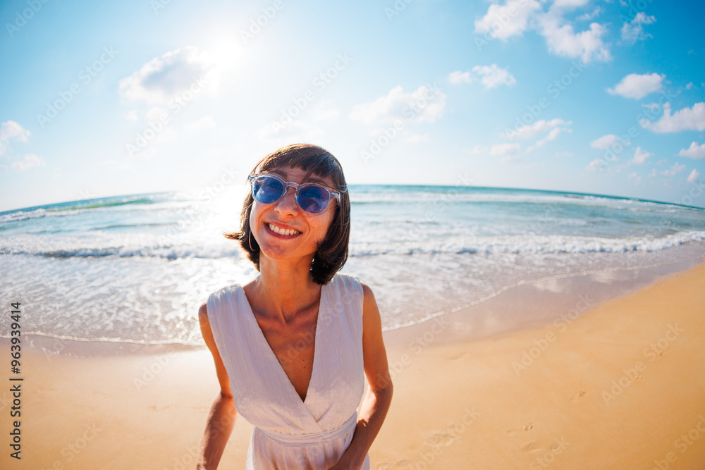 young pretty cheerful girl in a summer dress and hat looks happily at the camera against the backdrop of the sea. young pretty cheerful girl in a summer dress and hat looks happily at the camera against the backdrop of the sea.