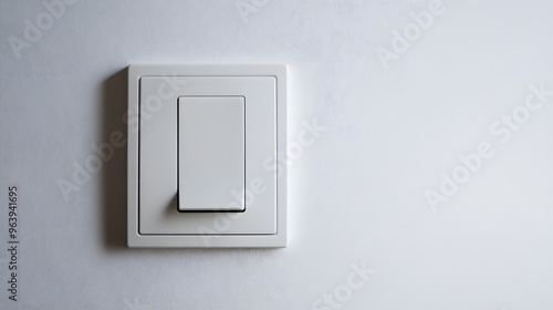 A close-up of a minimalist, modern light switch on a clean, white wall