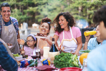 Joyful family barbecue, multigenerational outdoor dinner, diverse group laughing at summer picnic