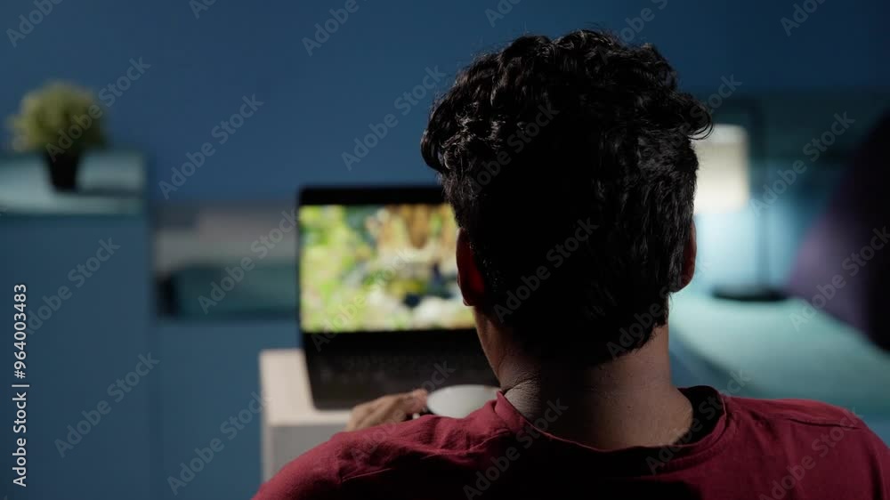 Person watching a video on a laptop while enjoying a cup of coffee, relaxing in a cozy indoor setting Person watching a video on a laptop while enjoying a cup of coffee, relaxing in a cozy indoor setting