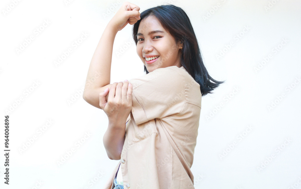 happy asian woman celebrate victory with raised fist wearing casual brown clothes isolated on white background happy asian woman celebrate victory with raised fist wearing casual brown clothes isolated on white background