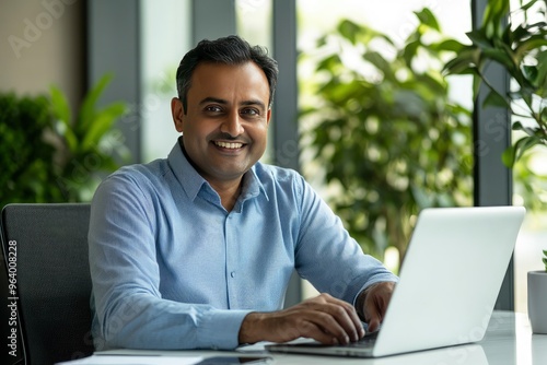 Smiling mature business man executive wearing shirt sitting at desk using laptop. Happy busy professional middle aged Indian businessman investor working on computer looking away in office, ai