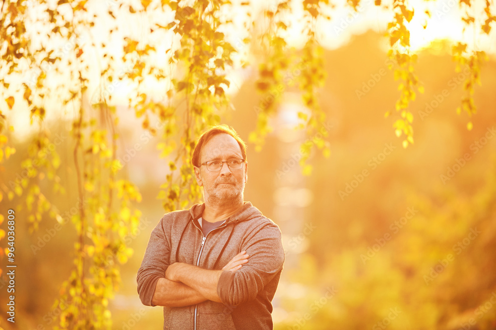 Obraz premium Outdoor portrait of 50 - 55 year old man enjoying nice bright morning or evening in rays of light