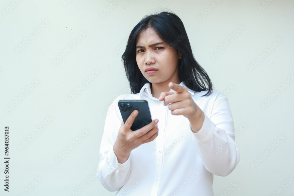 portrait of sad unbelieve asian business woman pointing to camera with glare eye holding smartphone, disappointment and disatisfied expression, wear formal white suit standing over isolated background portrait of sad unbelieve asian business woman pointing to camera with glare eye holding smartphone, disappointment and disatisfied expression, wear formal white suit standing over isolated background