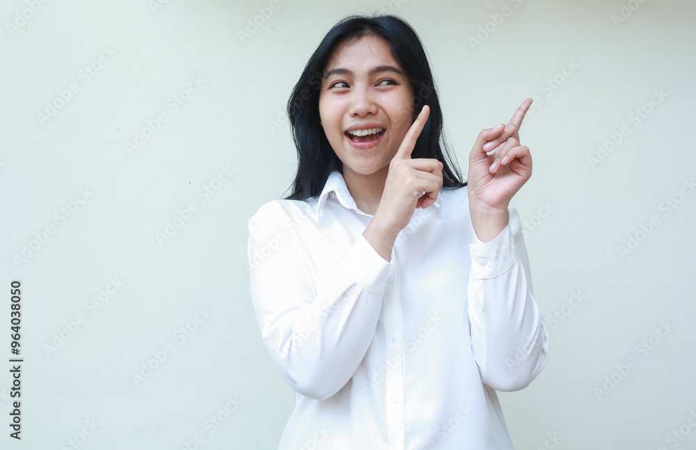 carefree asian young business woman wearing white formal suit shirt looking aside and pointing forefinger beside to empty space with excitement, presenting gesture, isolated on white background carefree asian young business woman wearing white formal suit shirt looking aside and pointing forefinger beside to empty space with excitement, presenting gesture, isolated on white background