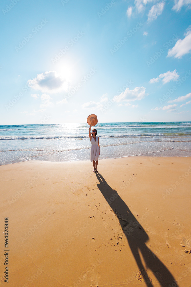 Obraz premium Happy woman enjoying the sun and sea. A carefree girl walks along the beach on a sunny day.
