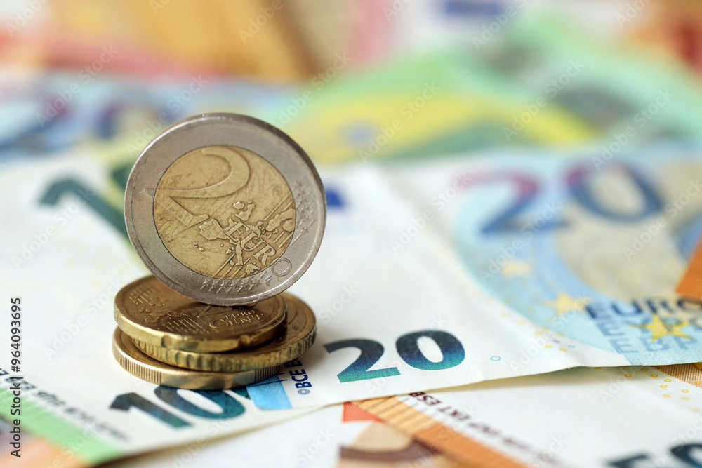 Two euro coin lies on huge amount of different euro dollars banknotes Two euro coin lies on huge amount of different euro dollars banknotes